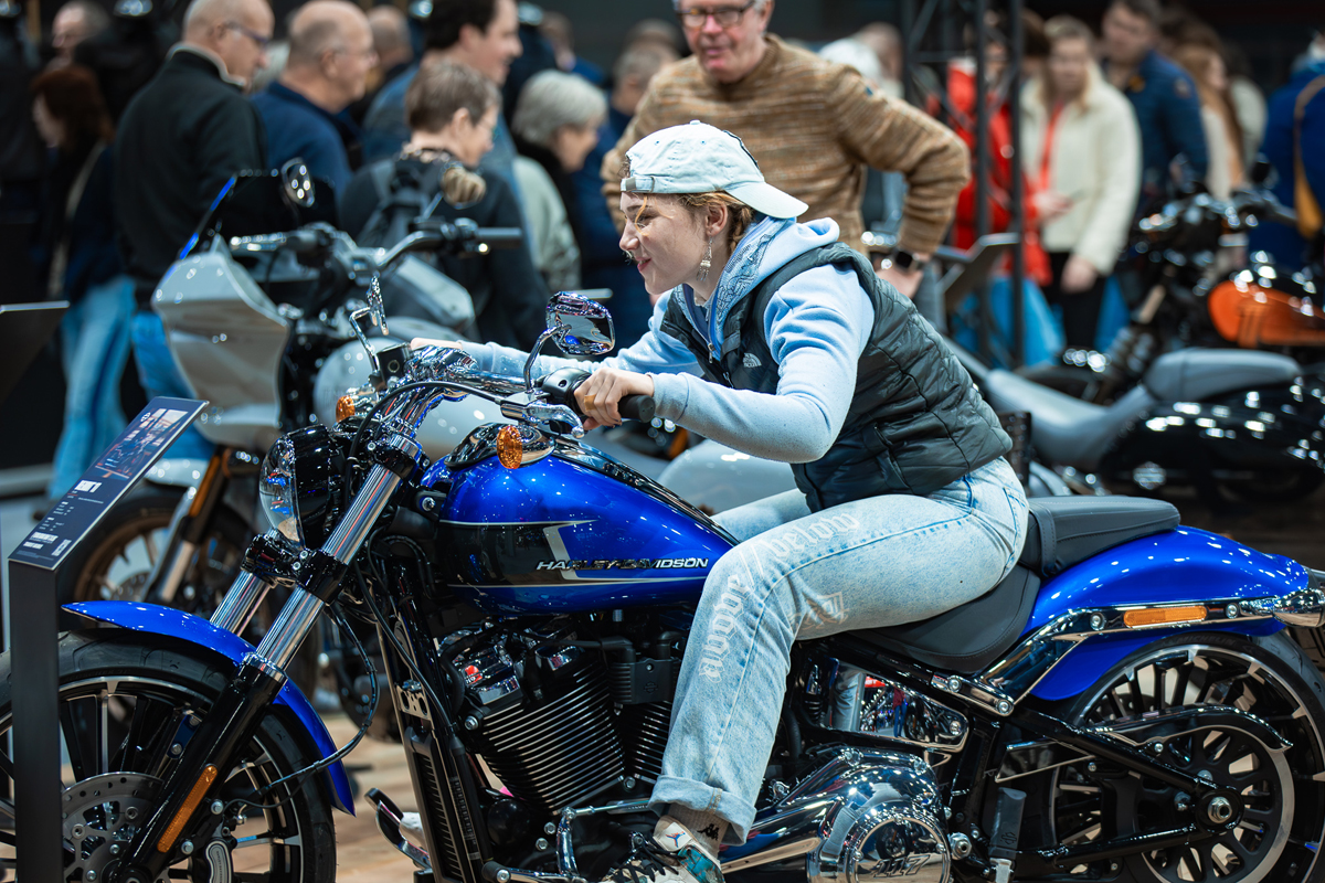 Vrouw met pet zit op Harley-Davidson motor