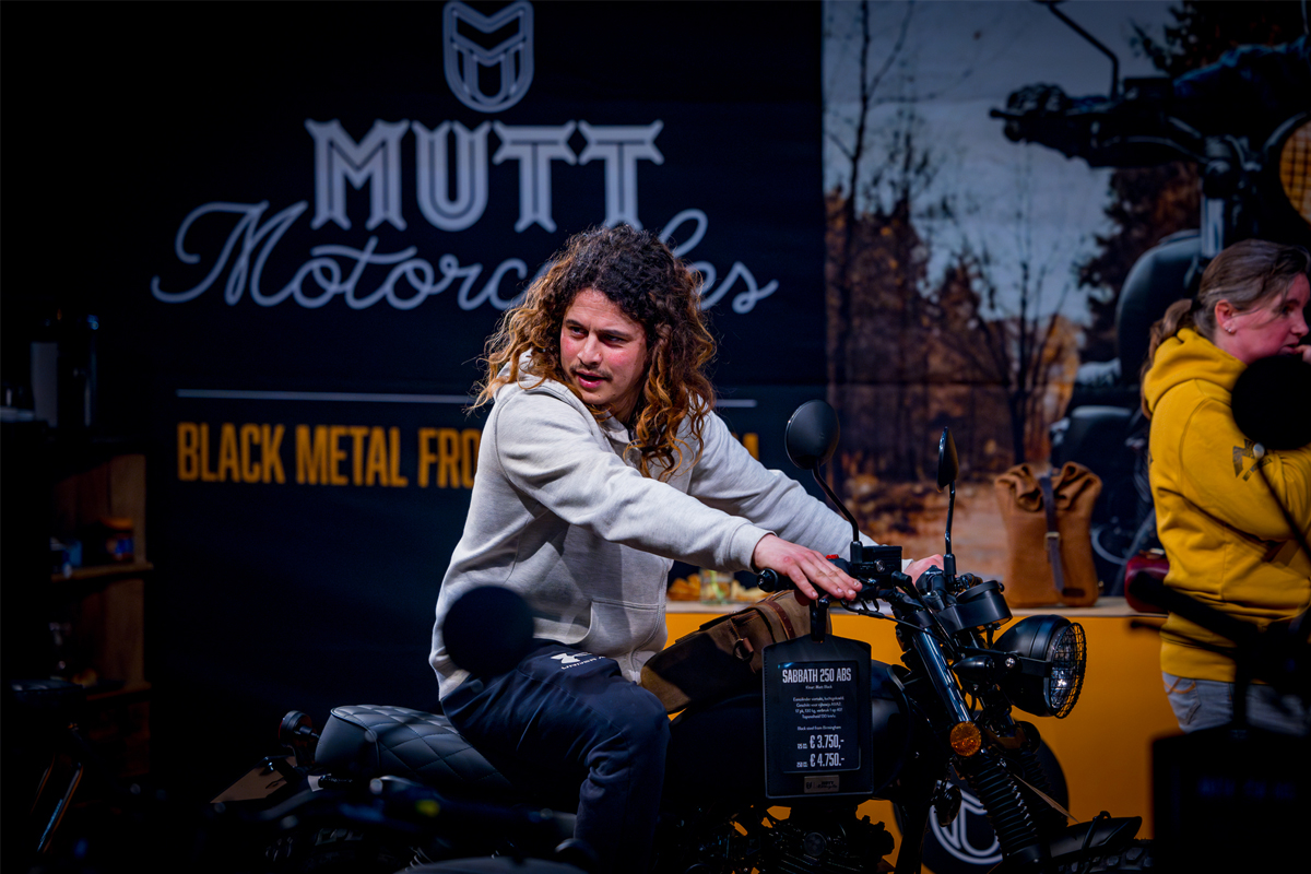 Man probeert motor uit in Mutt Motorcycles stand