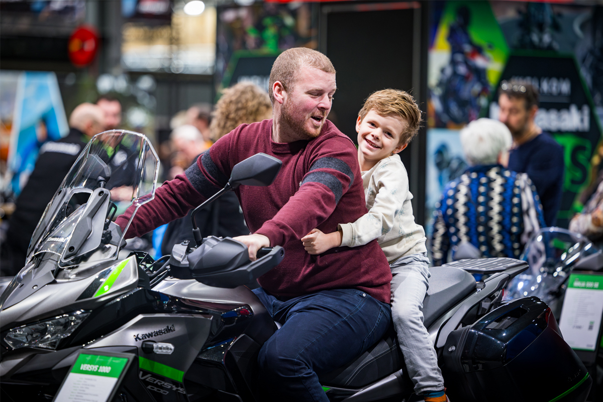 Vader en glimlachend zoontje zitten samen op motor
