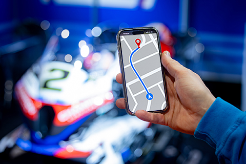 Telefoon met navigatie in hand met motor op achtergrond