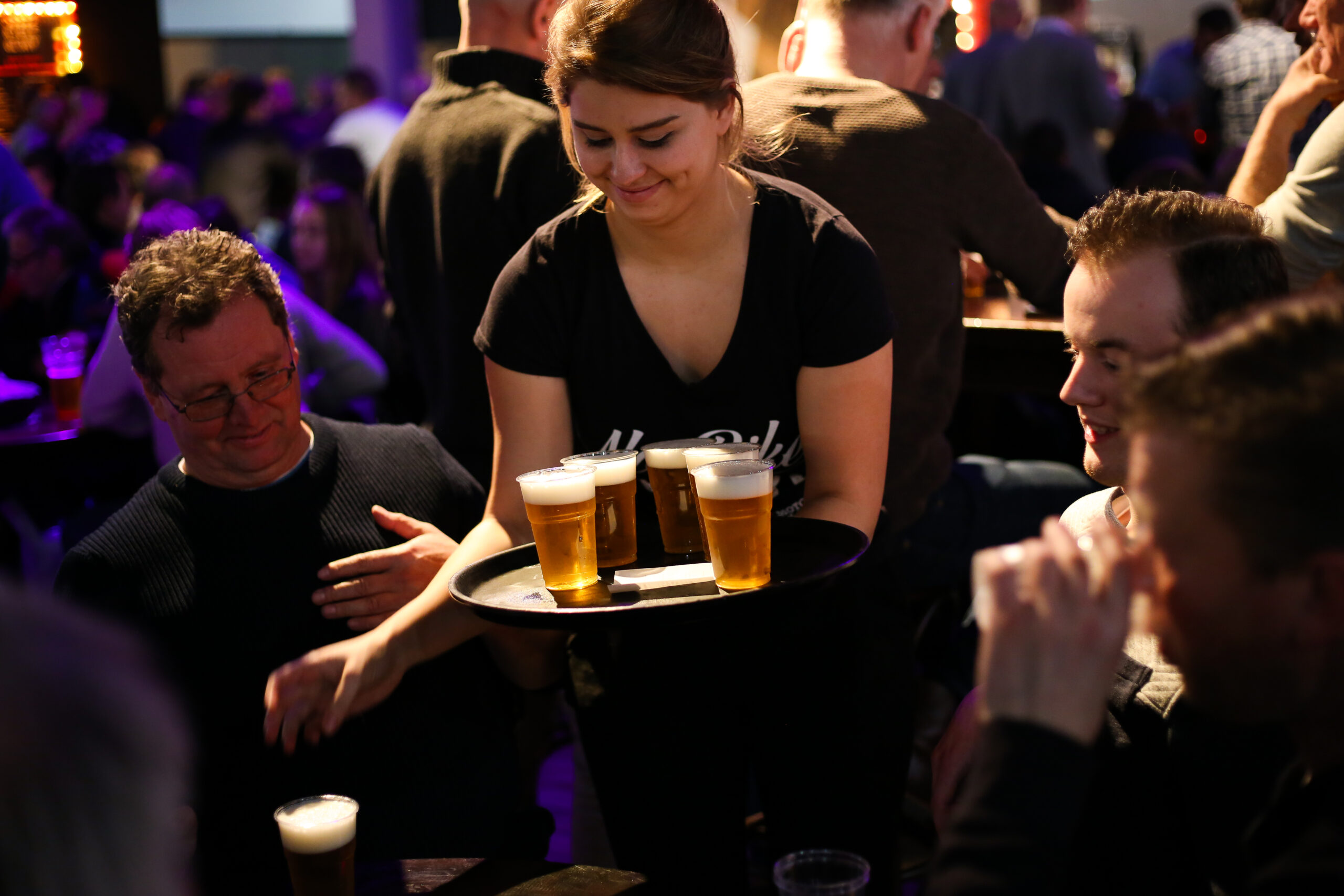 Barvrouw zet biertjes op tafel
